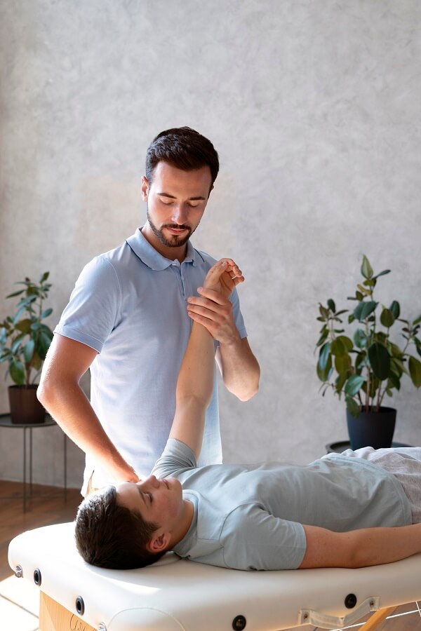 A male physical Therapist giving manual therapy to a male patient who is laying on the table.